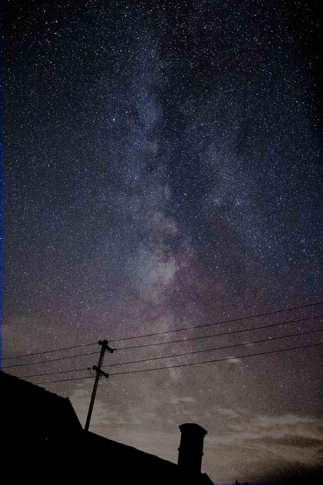 Die Milchstraße über einem Hausdach in Österreich