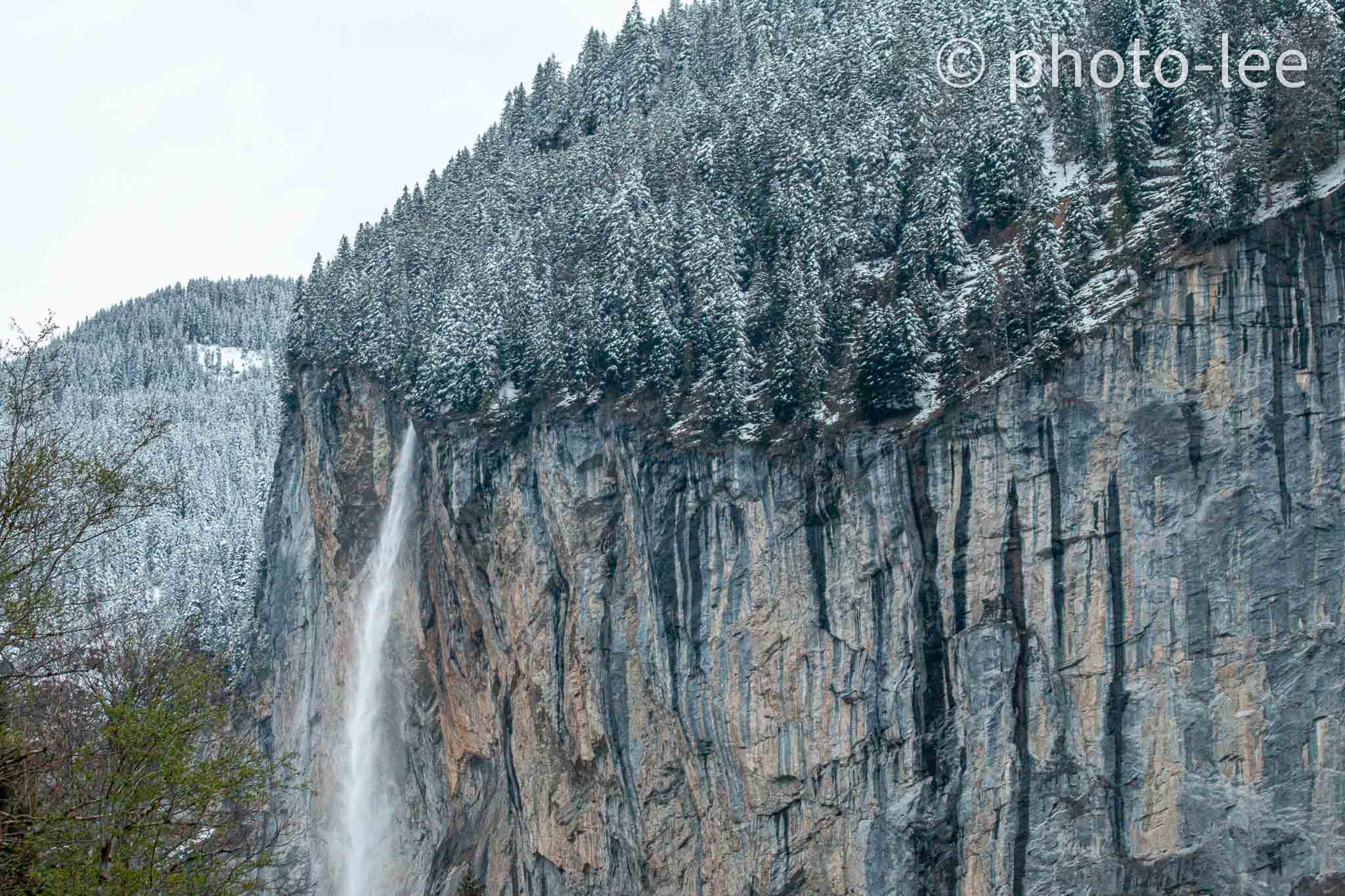 Ein Wasserfall am Rand eines - mit Bäumen bedeckten - Berges